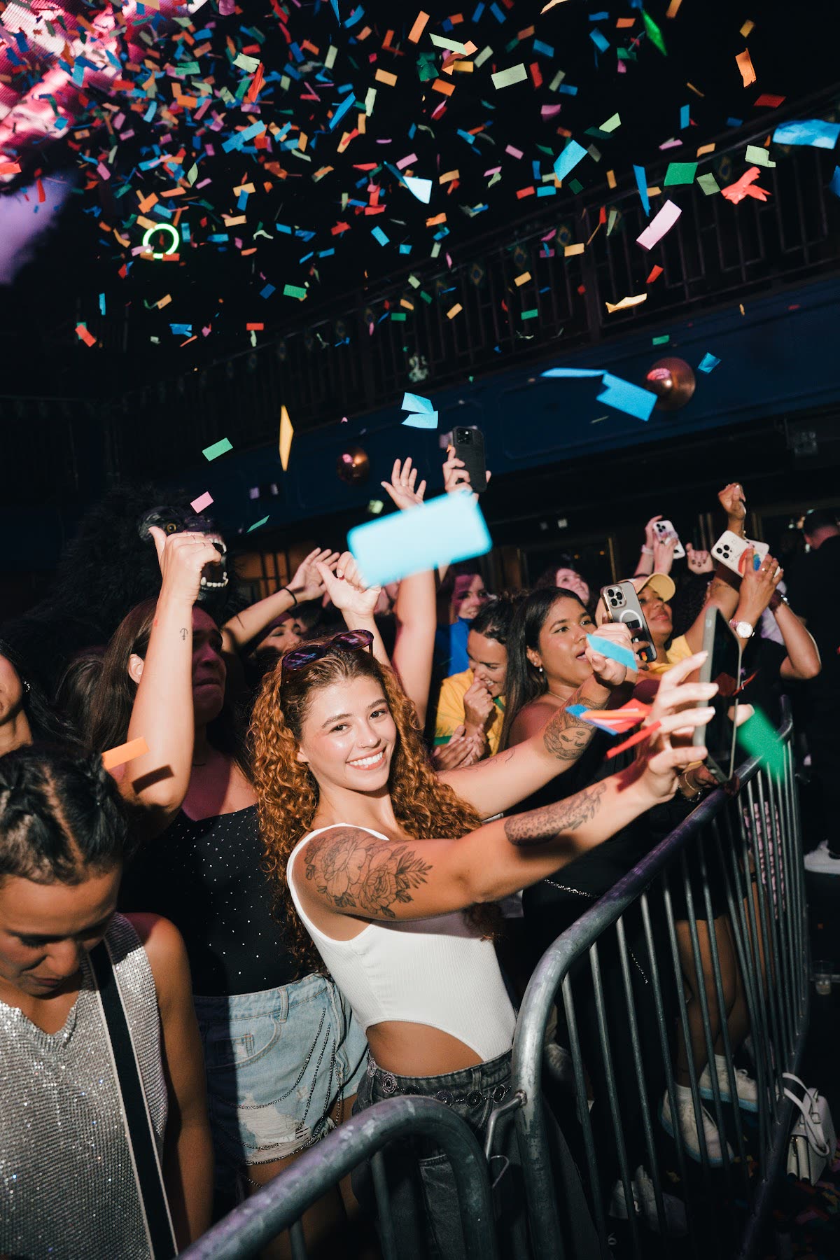 Nightclub crowd reaching up beneath falling confetti